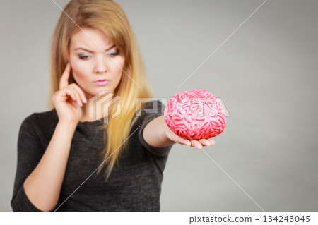 Woman thinking and holding fake brain Woman thinking and holding fake brain 134243045