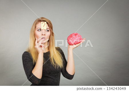 Woman thinking and holding fake brain Woman thinking and holding fake brain 134243049