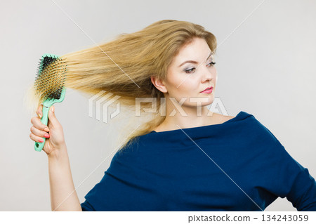 Woman brushing her long hair with brush Woman brushing her long hair with brush 134243059