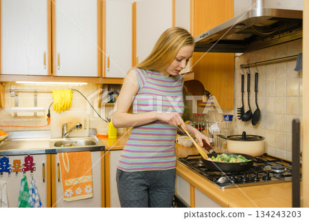 Woman cooking stir fry frozen vegetable on pan Woman cooking stir fry frozen vegetable on pan 134243203