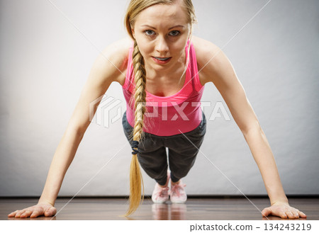 Woman training at home doing push ups 134243219