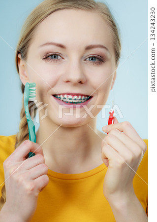 Girl with teeth braces using interdental and traditional brush 134243230