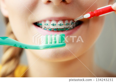 Girl with teeth braces using interdental and traditional brush 134243231