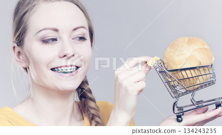 Woman holding shopping cart with bread Woman holding shopping cart with bread 134243235