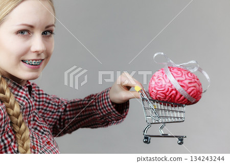 Woman holding shopping cart with brain Woman holding shopping cart with brain 134243244