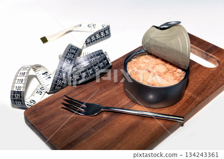 Tuna in open can with measuring tape for weight loss concept. Tuna in open can with measuring tape for weight loss concept. 134243361