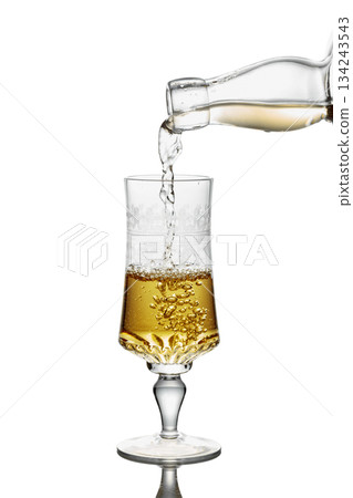 Gold liquor pouring into a glass on a white background. Gold liquor pouring into a glass on a white background. 134243543
