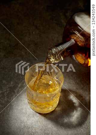 Whisky pour from a bottle into a crystal glass. 134243549