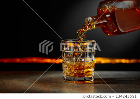 Whiskey is poured into a crystal glass. Whiskey is poured into a crystal glass. 134243551