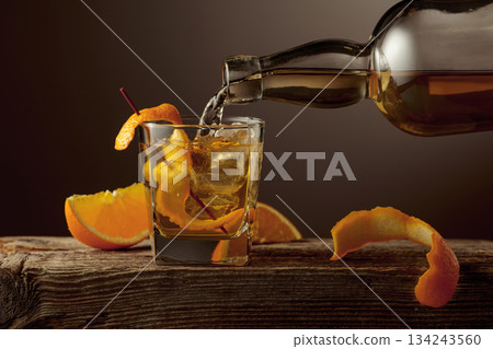 Old Fashioned cocktail with ice and orange peel on a old wooden table. Old Fashioned cocktail with ice and orange peel on a old wooden table. 134243560