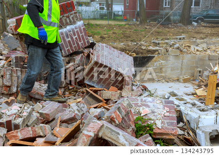 Construction worker removes debris from demolished building site in residential Construction worker removes debris from demolished building site in residential 134243795