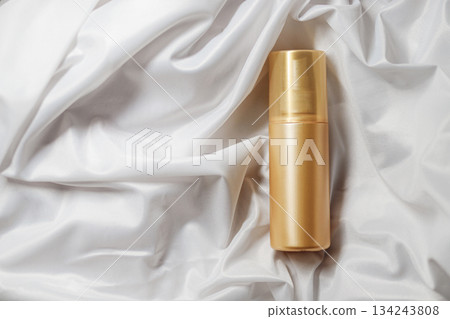 Mock up golden spray bottle for cosmetics on elegant white satin backdrop Mock up golden spray bottle for cosmetics on elegant white satin backdrop 134243808