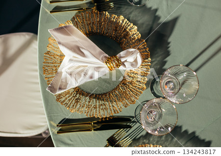 Top-down view of luxury table setting with gold charger plates and napkin rings 134243817