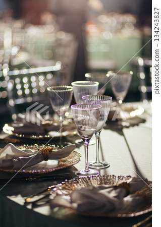 Sunlit close-up of luxury table setting with glowing crystal glasses Sunlit close-up of luxury table setting with glowing crystal glasses 134243827