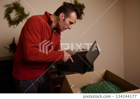 Man Packing Laptop Into Box for Holiday Gift and Move at Home During Christmas 134244177