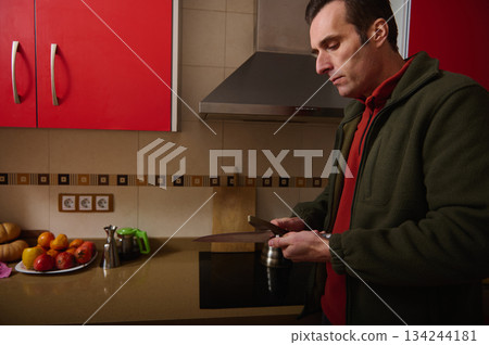 Man Preparing Food in Modern Kitchen, Slicing with Knife Near Fresh Fruits 134244181