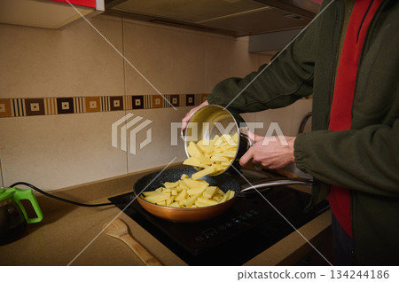 Home Cooking: Person Pouring Potatoes Into Frying Pan On Stove In Kitchen 134244186