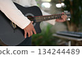 Black Acoustic Guitar In Hand Classic Body Nail Detail Under Soft Light, Keyboard Background 134244489