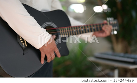 Black Acoustic Guitar In Hand Classic Body Nail Detail Under Soft Light, Keyboard Background Black Acoustic Guitar In Hand Classic Body Nail Detail Under Soft Light, Keyboard Background 134244489