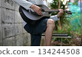 Black Acoustic Guitar With Gray Shirt Hand Playing, Against Gray Wall Green Outdoor Background, Alternative Sound 134244508