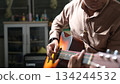 Acoustic Guitar Serenade Brown Shirt, Hand, Natural Light, And Sound hole In Indoor Setting 134244532