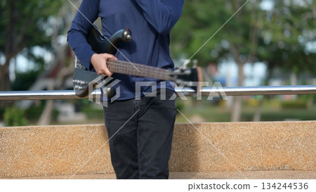 Bass Guitarist Against Light Brown Wall Outdoor Night Ambition, Building Future Trust, Dark Body Background 134244536