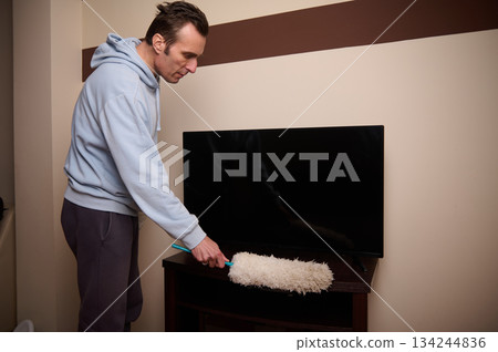 Man Cleaning TV Stand With Mop In Living Room After Sitting Area Upgrade Man Cleaning TV Stand With Mop In Living Room After Sitting Area Upgrade 134244836
