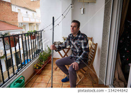 Man On Balcony With Monopod Looking Thoughtful In Plaid Shirt During Christmas Season Man On Balcony With Monopod Looking Thoughtful In Plaid Shirt During Christmas Season 134244842