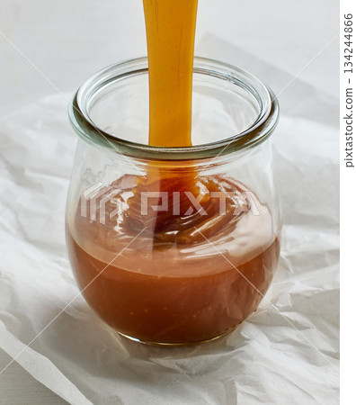 freshly cooked homemade caramel sauce pouring in jar 134244866