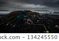 A mountain of fishing nets and marine plastic waste washed up on a stormy beach 134245550