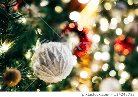 White ornament decorating christmas tree branches with bokeh lights 134245782