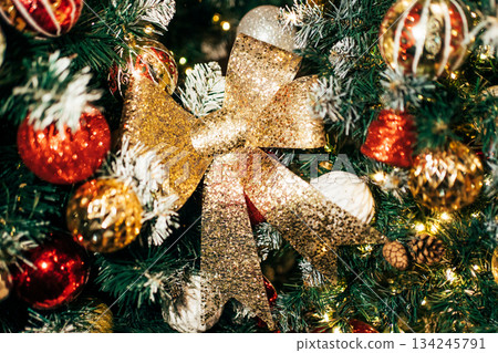 Christmas tree decorating with glittering gold bow and ornaments 134245791