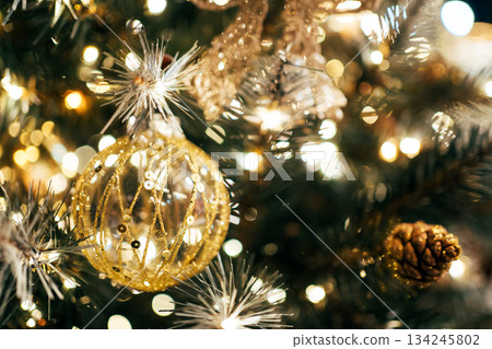 Christmas tree glowing with festive gold ornament and lights Christmas tree glowing with festive gold ornament and lights 134245802