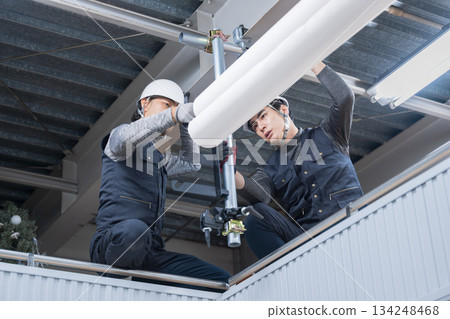 Construction work such as clamping single-pipe pipes on high scaffolding near the ceiling. Image of construction workers and workers Construction work such as clamping single-pipe pipes on high scaffolding near the ceiling. Image of construction workers and workers 134248468