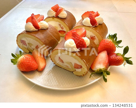 Soft roll cake with fluffy sponge layers and creamy filling spiraled inside, showcasing smooth texture, delicate shape, and sweet inviting appearance in close-up detail 134248531