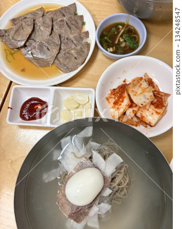 Authentic Pyongyang naengmyeon with chewy buckwheat noodles in cold, clear broth, offering a refreshing and delicate flavor. Perfect for traditional Korean cuisine menus and summer dishes. 134248547