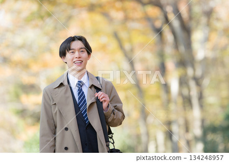 一位身穿外套的男士在秋葉環繞下外出辦事。 134248957