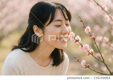 一位日本女性臉上帶著柔和的表情，享受著梅花的芬芳。 134249064