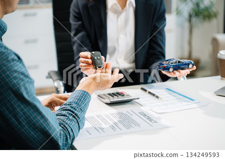Business professionals finalize a car sale agreement with paperwork and model car, capturing themes Business professionals finalize a car sale agreement with paperwork and model car, capturing themes 134249593