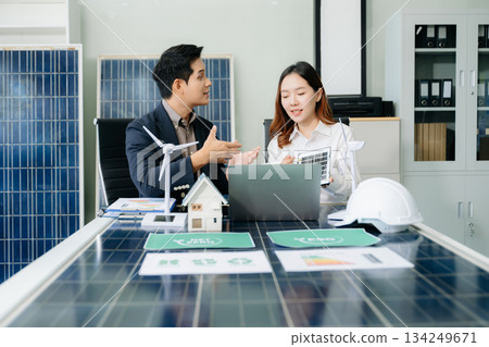 Engineers discuss solar panels and turbines in office, working on clean energy design, sustainable power Engineers discuss solar panels and turbines in office, working on clean energy design, sustainable power 134249671
