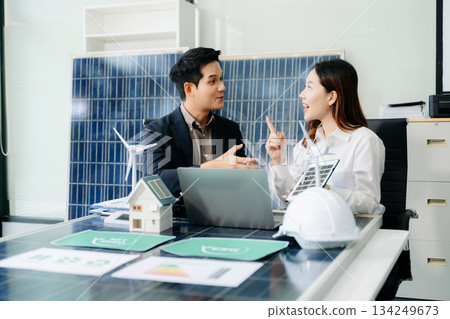 Engineers discuss solar panels and turbines in office, working on clean energy design, sustainable power Engineers discuss solar panels and turbines in office, working on clean energy design, sustainable power 134249673
