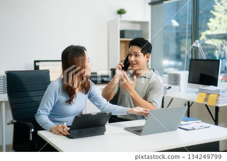 Two business workers talking on the smartphone and using laptop 134249799