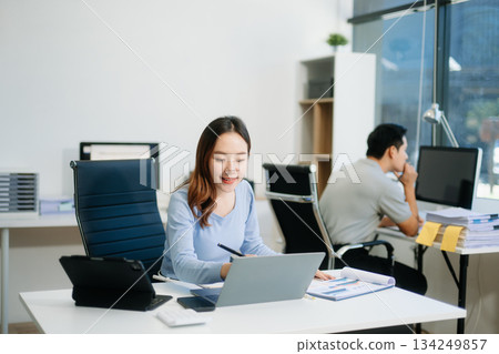 Asian business woman typing laptop and tablet Placed at the table at the office Asian business woman typing laptop and tablet Placed at the table at the office 134249857