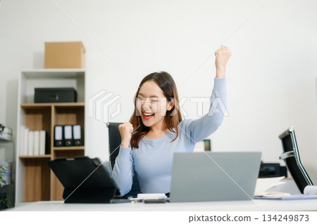 Asian business woman are delighted and happy with the work they do on their tablet, laptop and taking notes Asian business woman are delighted and happy with the work they do on their tablet, laptop and taking notes 134249873