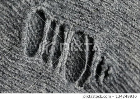 A close view of a gray sweater showing a rip and texture. A close view of a gray sweater showing a rip and texture. 134249930