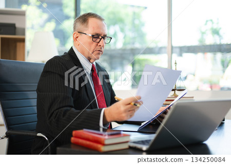 Mature Male judge in a courtroom on white table and Counselor or Male lawyer working in office. Justice and law concept 134250084