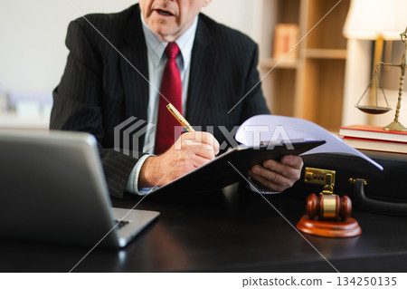 justice and law concept. Male judge in a courtroom the gavel, working with smart phone and laptop and digital tablet 134250135