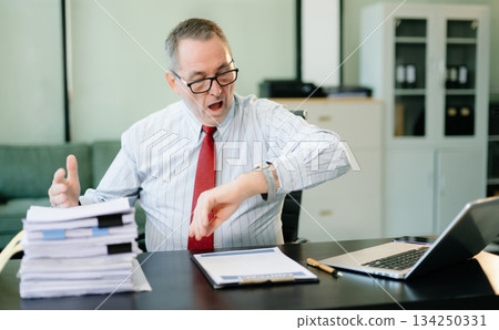 Frustrated Mature Businessmann working on a laptop computer sitting at his working place Frustrated Mature Businessmann working on a laptop computer sitting at his working place 134250331