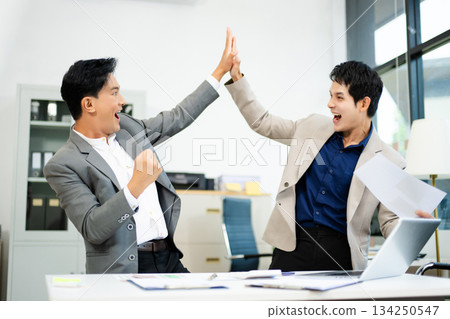Two excited businessmen cheering with joy in office after success. Concept of teamwork, business win 134250547