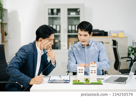 Two professional men analyzing house model and design layout in office. Ideal for themes of architecture, investment, real estate, property Two professional men analyzing house model and design layout in office. Ideal for themes of architecture, investment, real estate, property 134250579